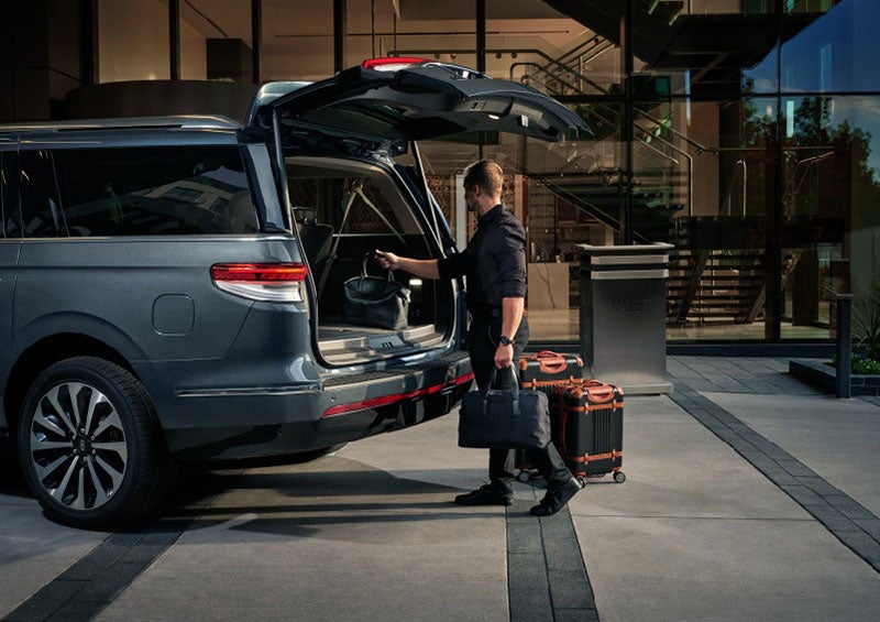 A valet is unloading luggage from the rear cargo area of a 2023 Lincoln Navigator SUV. | Wallace Lincoln in Fort Pierce FL